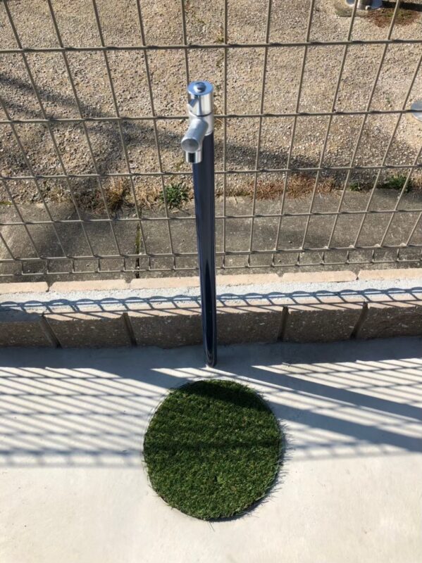 シンプルな立水栓。雨水マスの上に人工芝のアクセント。
